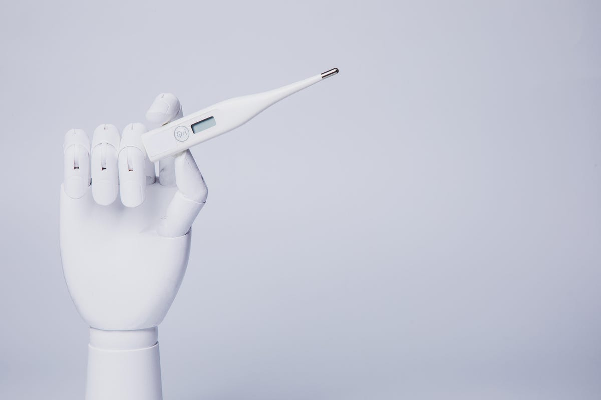 A robotic hand holding a thermometer against a light purple background