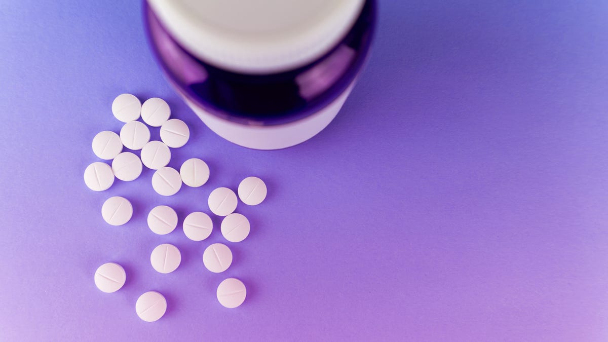 Bottle with melatonin pills or supplements, purple background