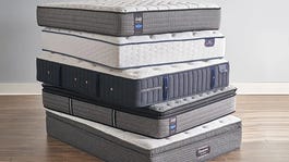 A stack of gray mattresses on a hardwood floor.